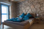 <p>Schlafzimmer mit massivem Bett und Natursteinmauer</p>